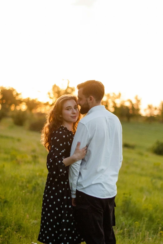 two people standing next to each other near trees