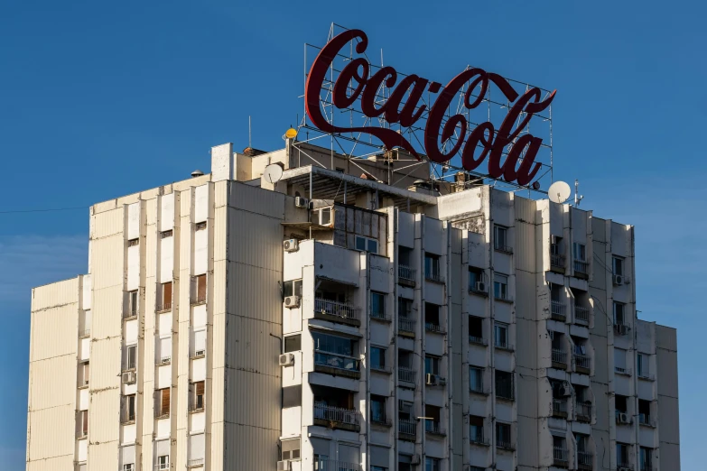 a very tall building has a giant coke cola sign on top