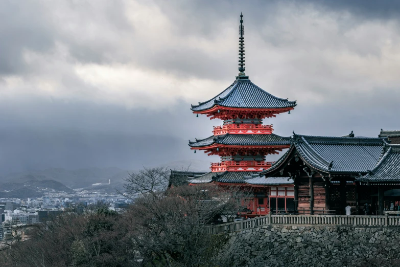 the tall pagoda is situated atop a hill with buildings on top