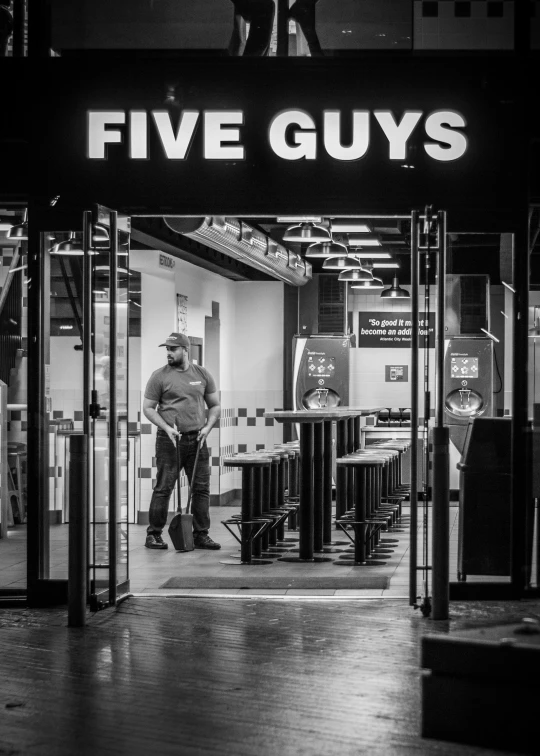 a man is standing outside of a five guys store