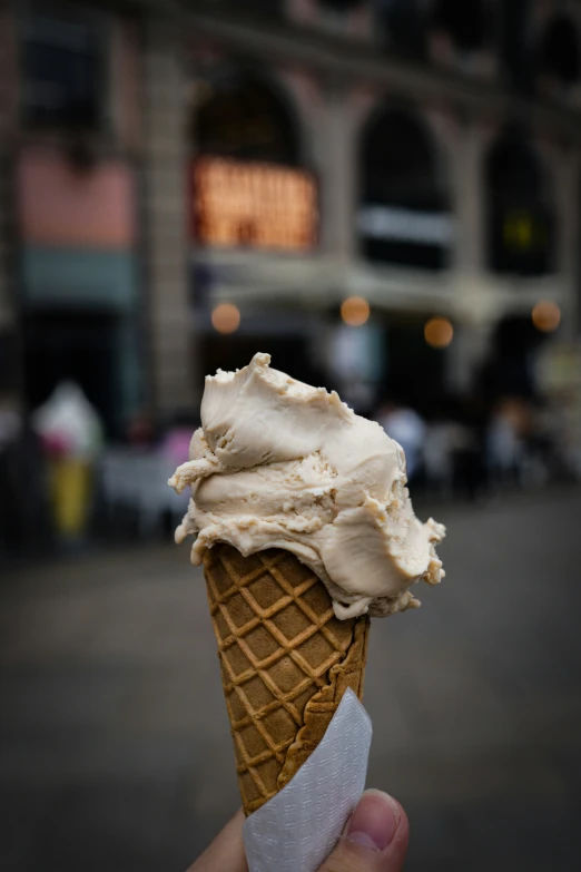 a hand is holding an ice cream cone that has been frosted