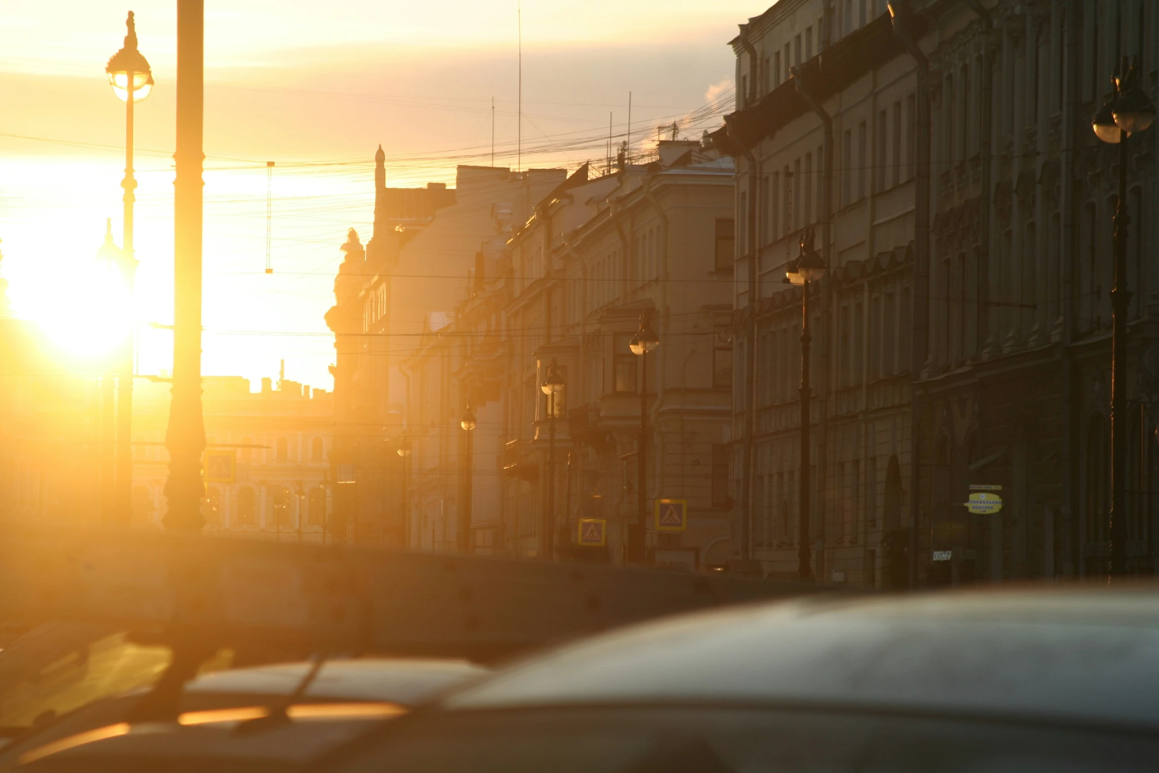 a city street with the sun setting behind buildings