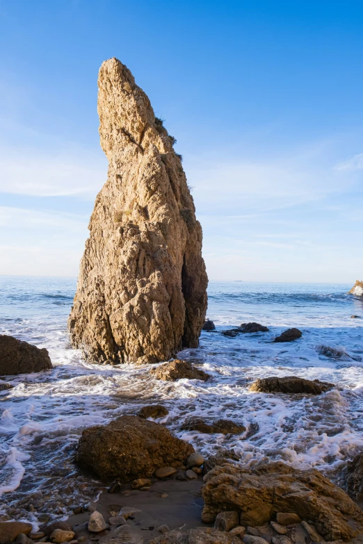 a large rock is sitting by the beach