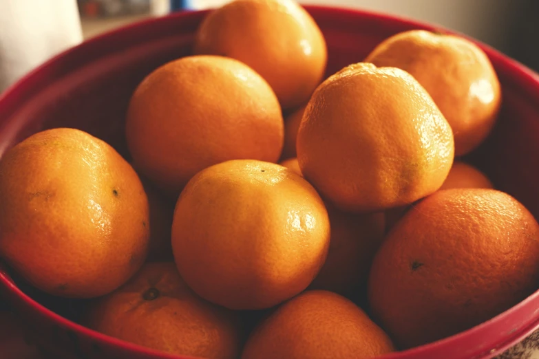 the oranges are in the red bowl on the counter