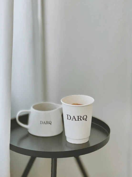 two cups are on a table by the window