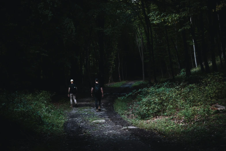 two men walking down the middle of a trail