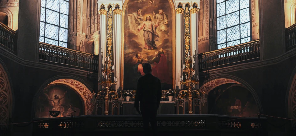 a man stands in a church looking out into a building