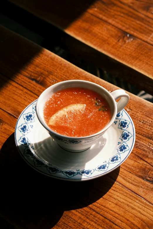 a bowl full of tomato soup sitting on top of a blue and white plate