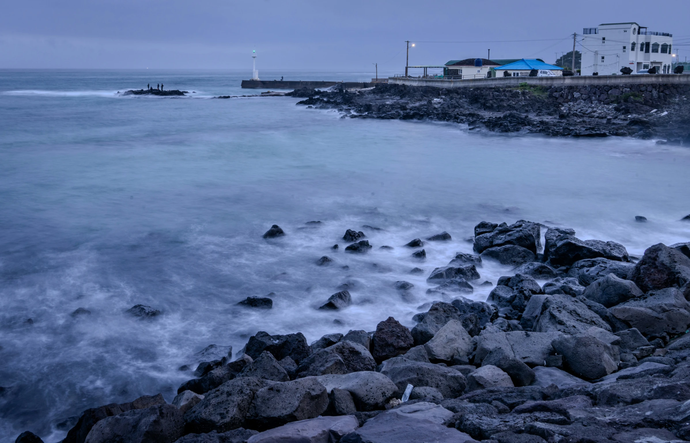 water waves are crashing into the rocks near a house