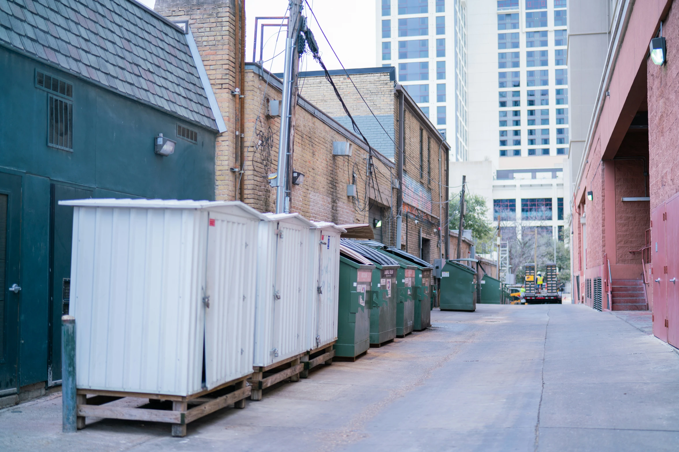 a narrow street with a row of shipping containers and a tall red brick building