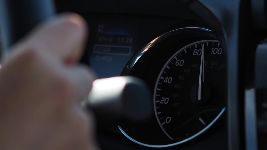 a car dashboard with meters on and hand pointing at it