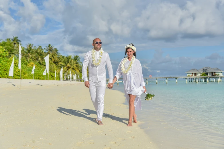 two newly married couples walking on the beach