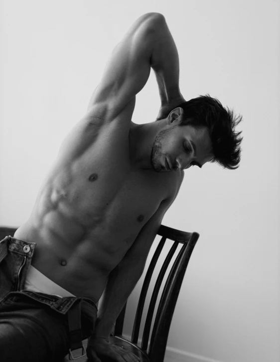 a male shirtless man is posing on a chair