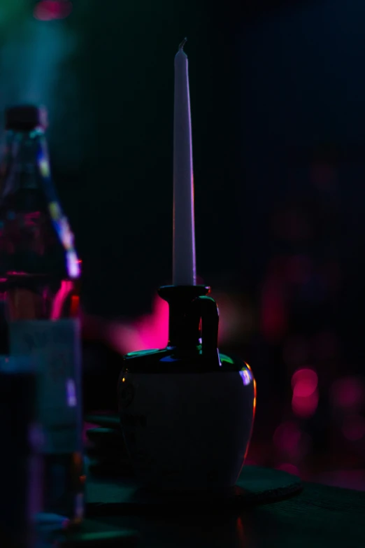 candlestick sitting on table with bottles and lighting behind