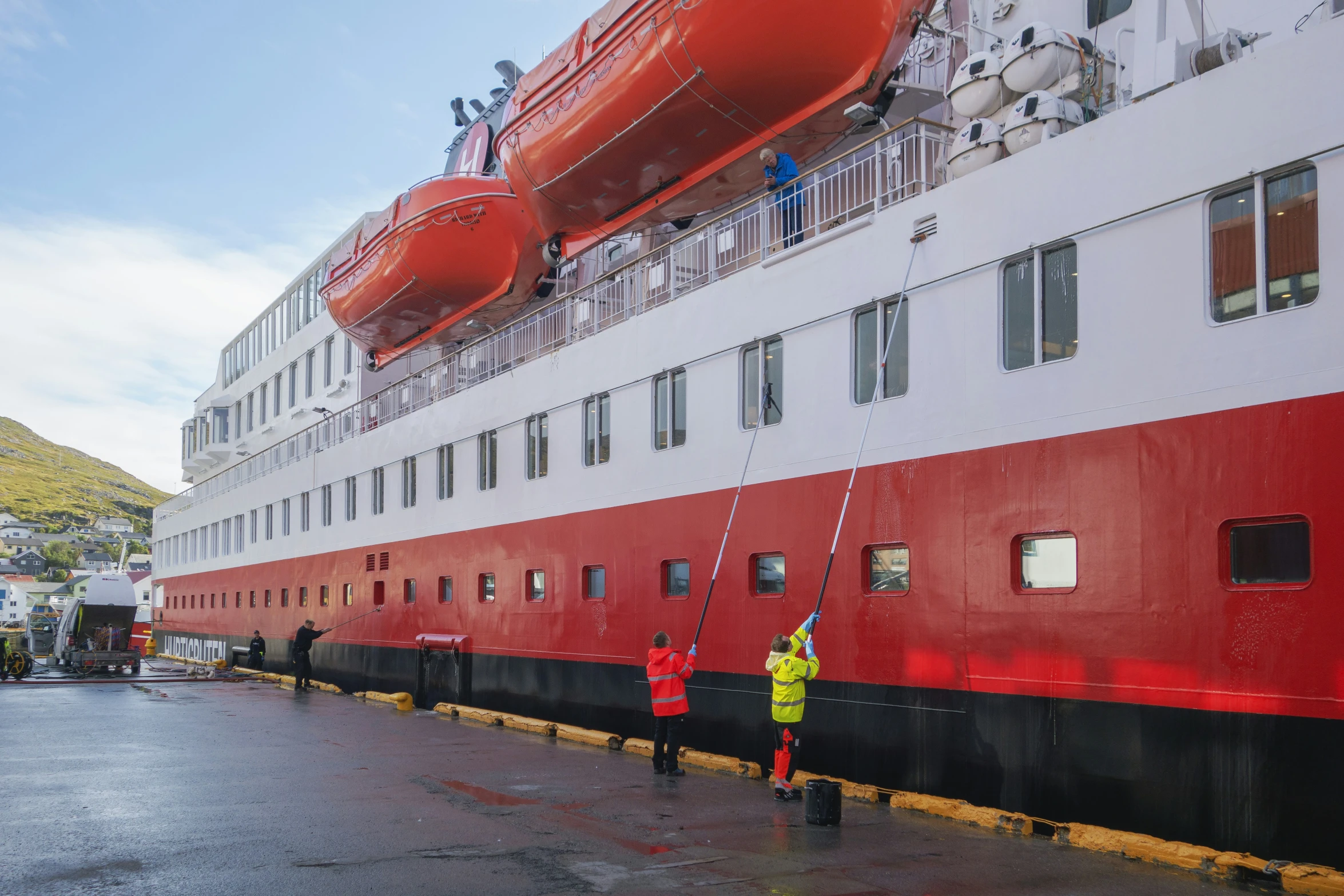 red and white ship being cleaned with a hose