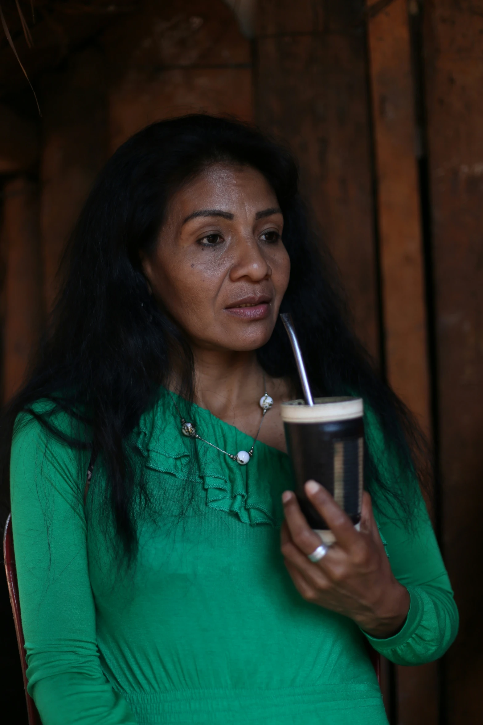 a woman holding a cup is using the pipe to smoke