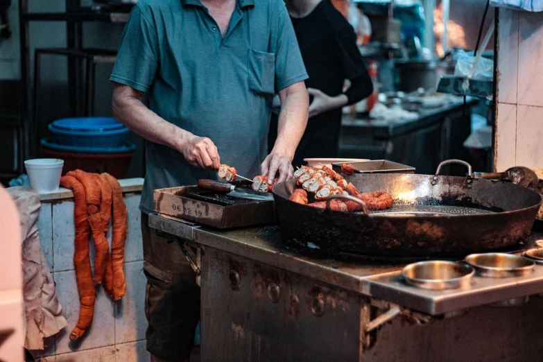 a man grilling several different types of meats on an outdoor grill