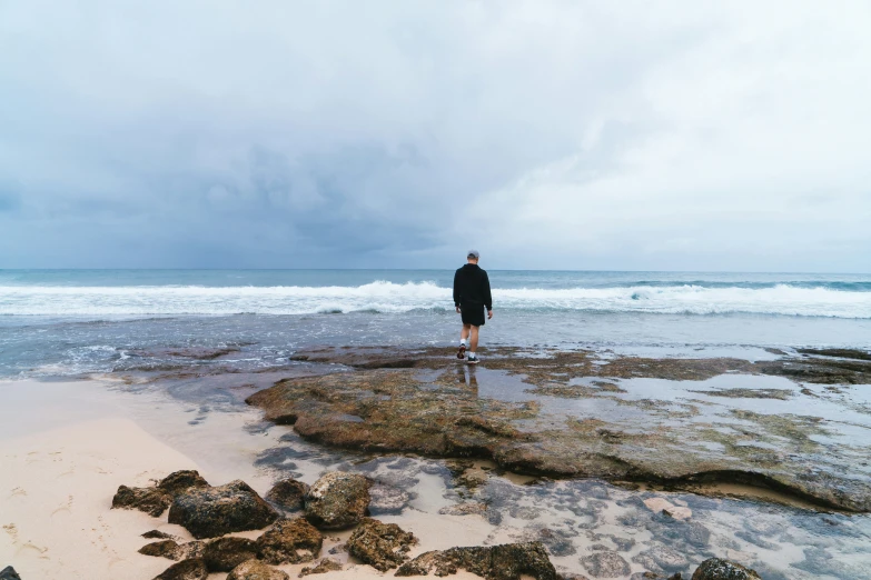 a man looking out on the water with dark clouds in the background