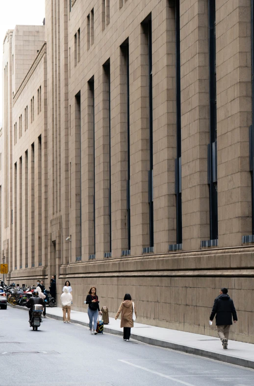 people walking and standing along a sidewalk on a city street