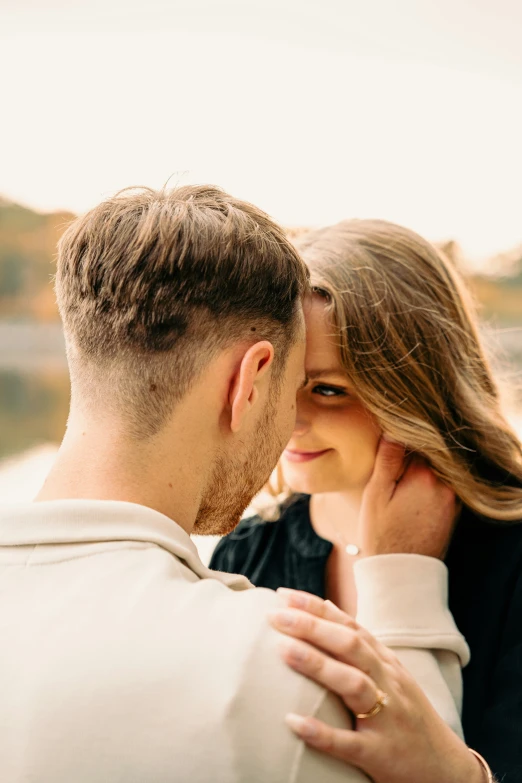 a close up of a couple's face with each other and a sunset in the background