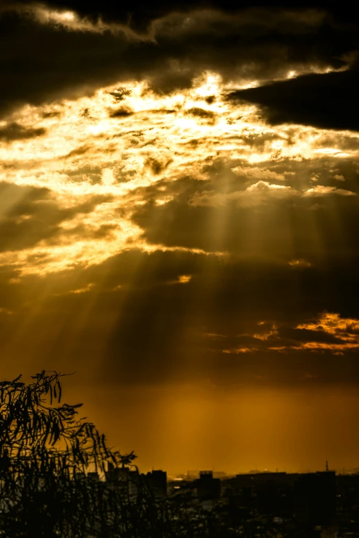 sun rays breaking through clouds, in the distance some buildings