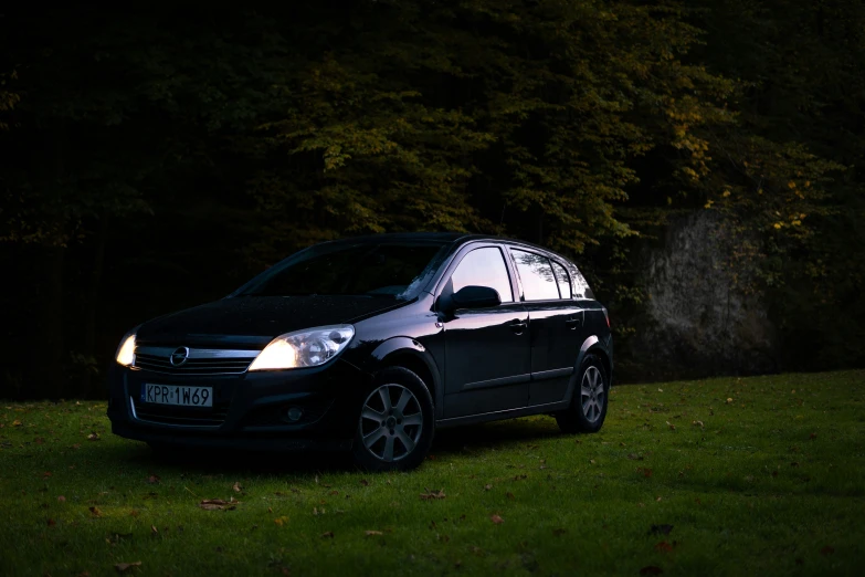 a small black van is on some grass and it's glowing