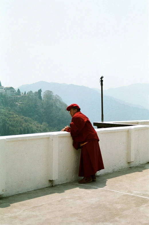 a monk leaning on a wall and looking at soing