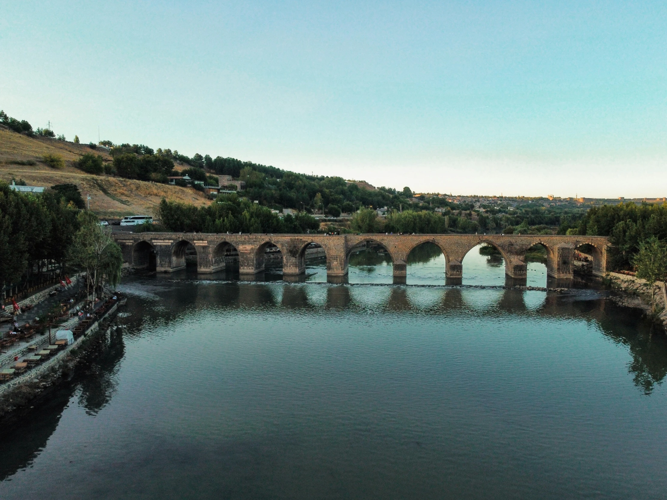 a large bridge spanning a river next to a forest