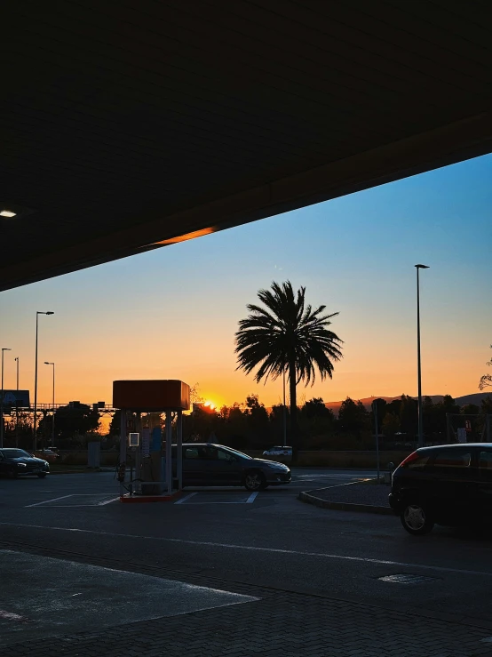 sunset reflecting off a gas station's horizon, taken from the parking lot