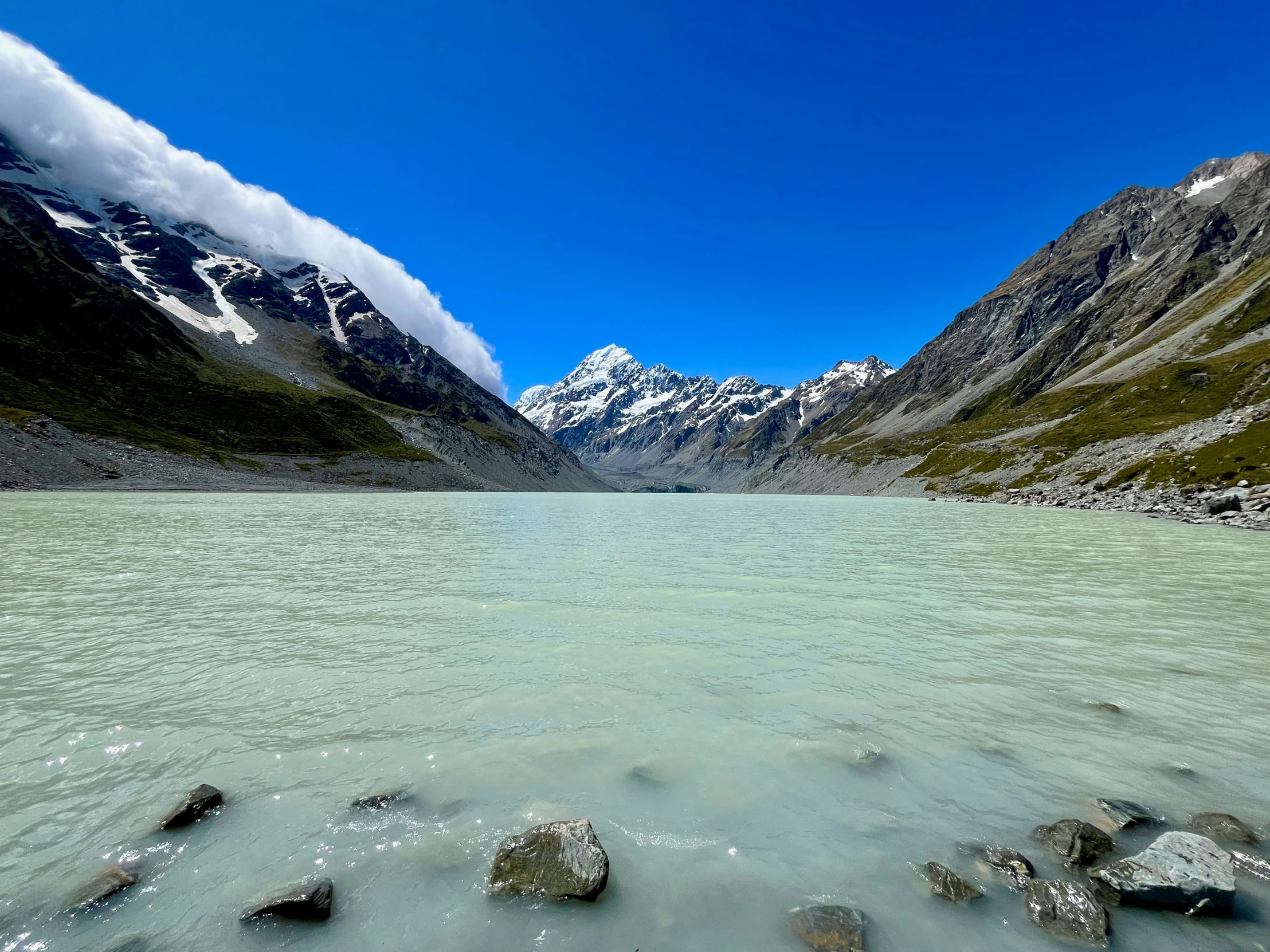 a clear lake surrounded by mountains in the background