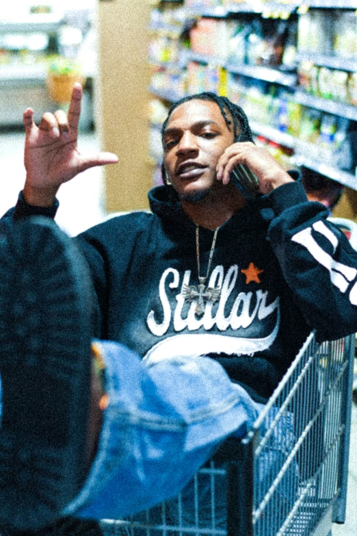 a man sitting in a shopping cart with one hand and another holding his head in the back of his stroller