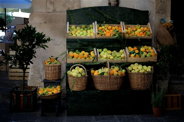 an outdoor stand holding apples, oranges and other fruit