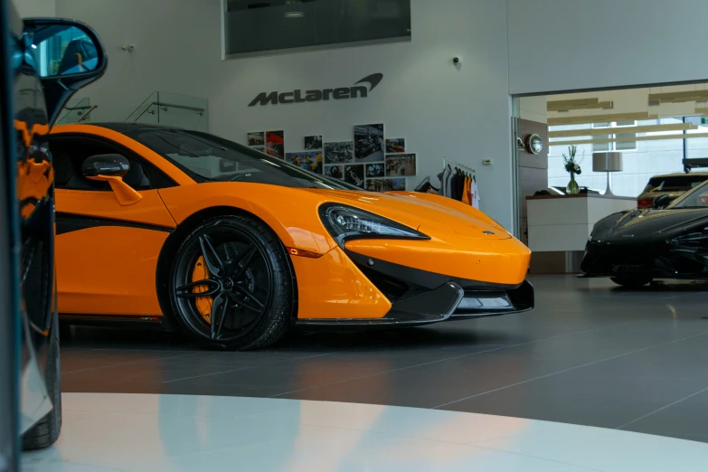 an orange car parked inside of a showroom