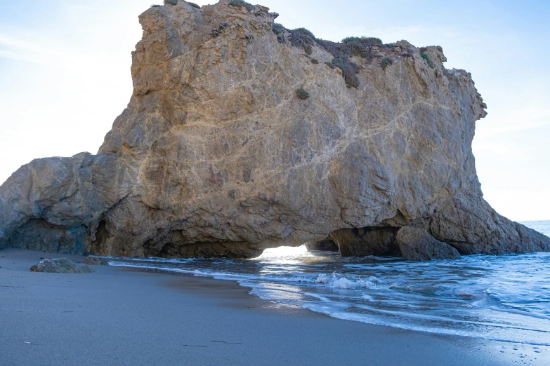 an arch made from rocks on the beach