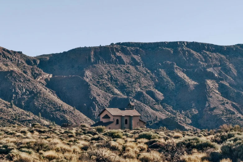 the small building sits in front of the large mountain