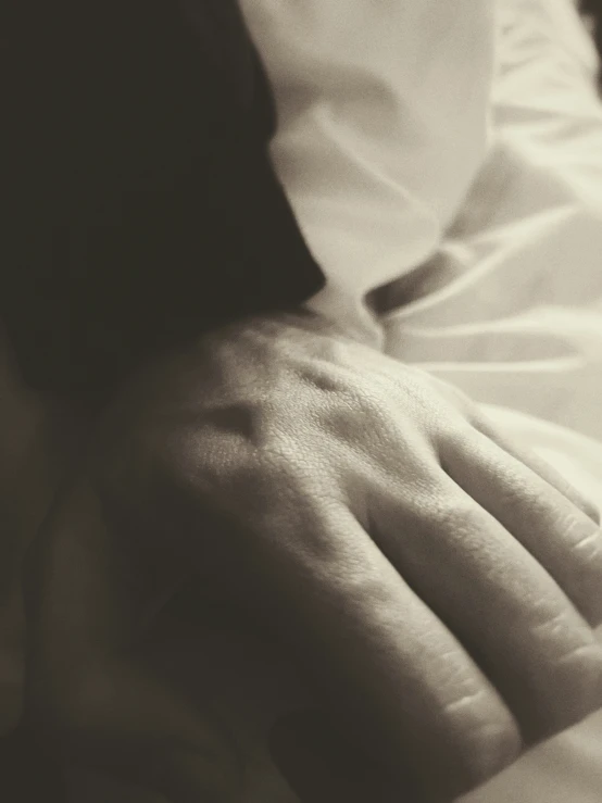 two hands touching each other in front of a white sheet