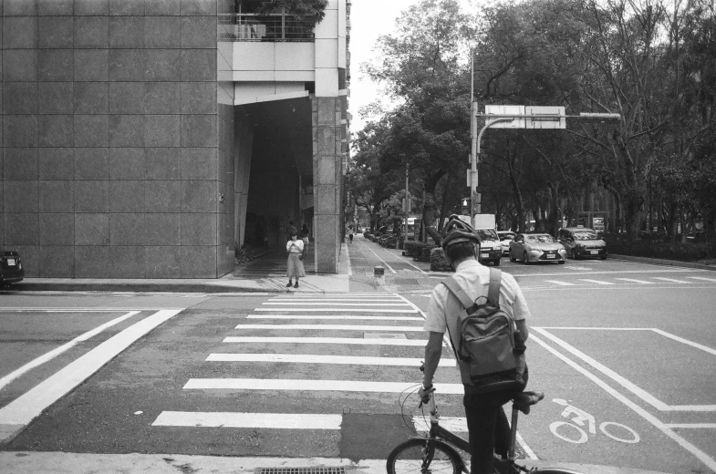 a bicyclist is stopped at a crosswalk as a man walks with his bike across the street