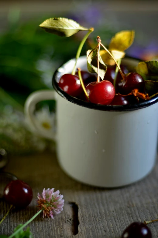 small cherries in a mug on the wooden table