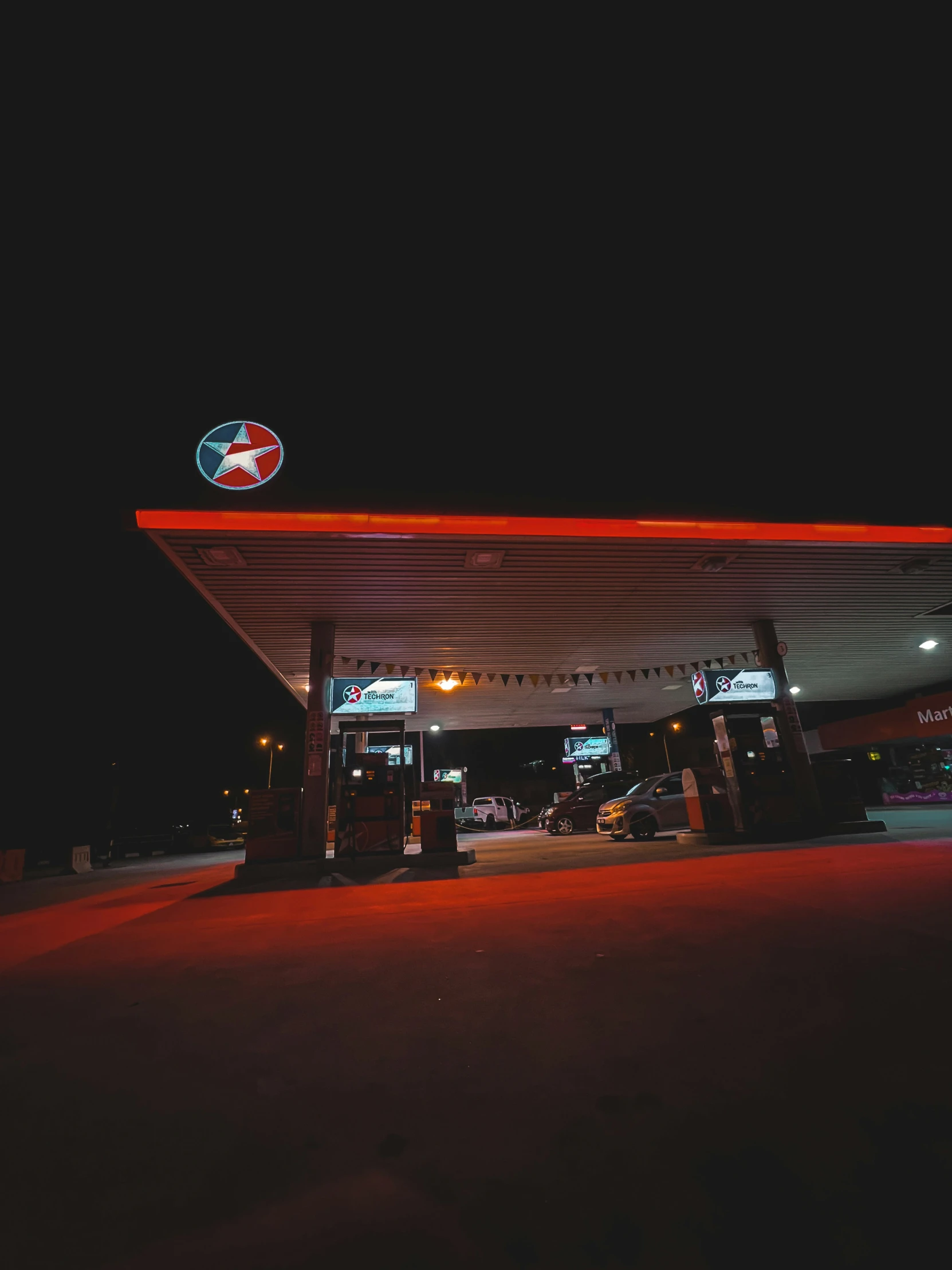 a gas station with a neon sign on top of it