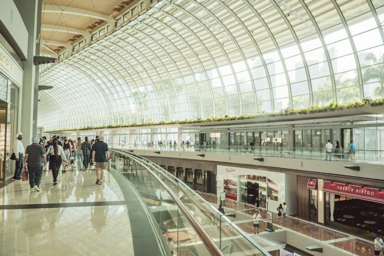 people walk inside a shopping mall with glass walls