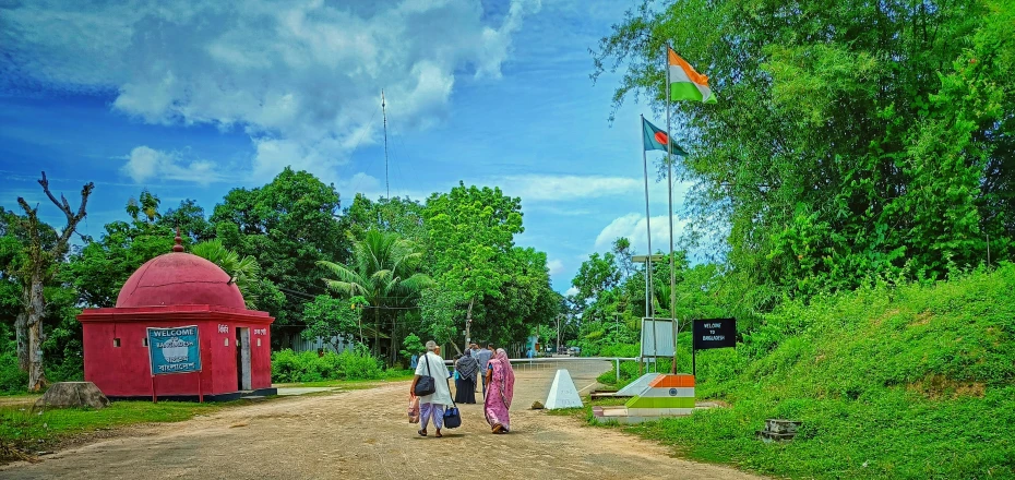 people walk toward a red structure at the entrance to a park