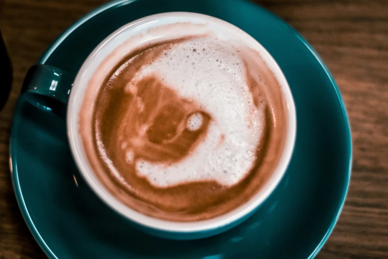 a cappuccino sits on a saucer on a table