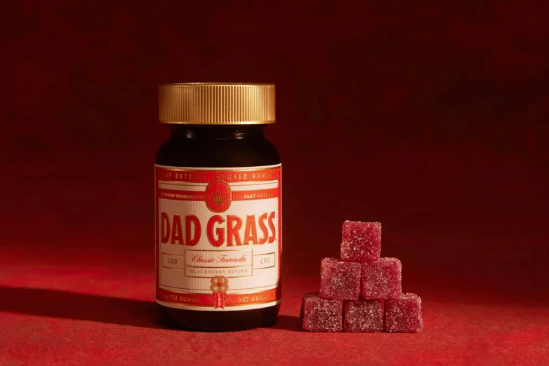 a bottle and blocks of pink sugar next to red backdrop