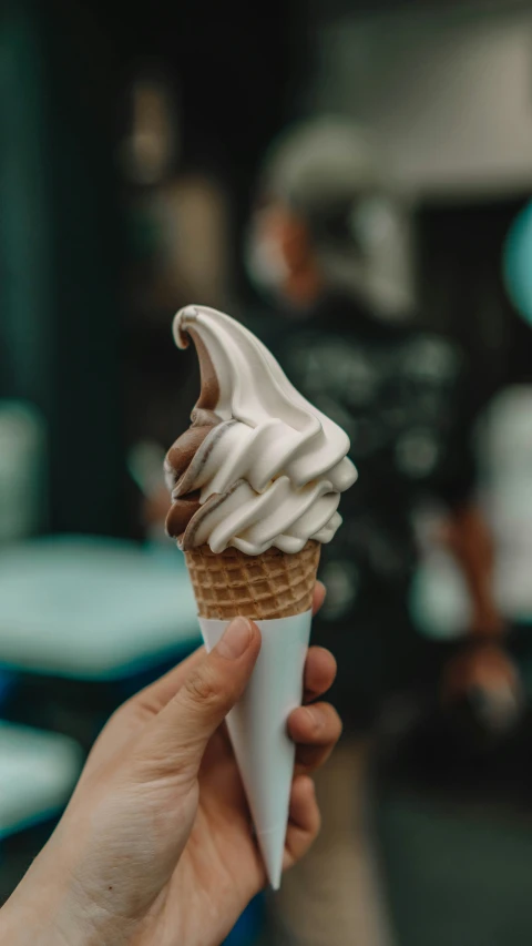 a person holding up a white cone with a swirl in it