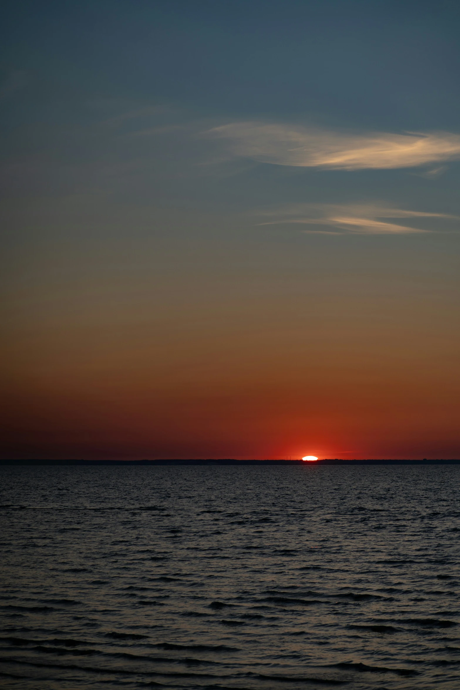 the sun setting over the horizon in a dark ocean