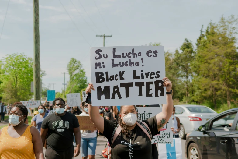 women marching down a street wearing face masks while holding up signs