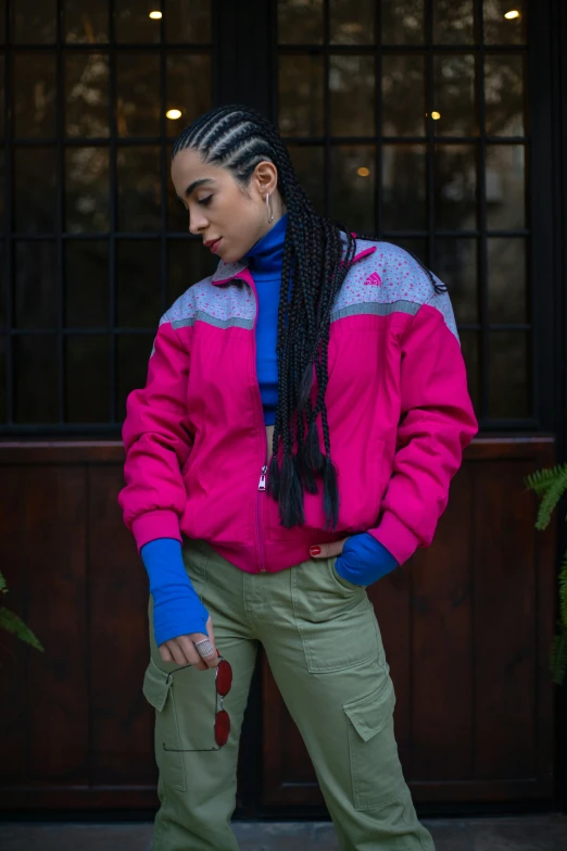 a woman is standing by herself while wearing pink and blue jacket