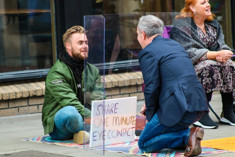 a man kneeling down on the ground by a sign