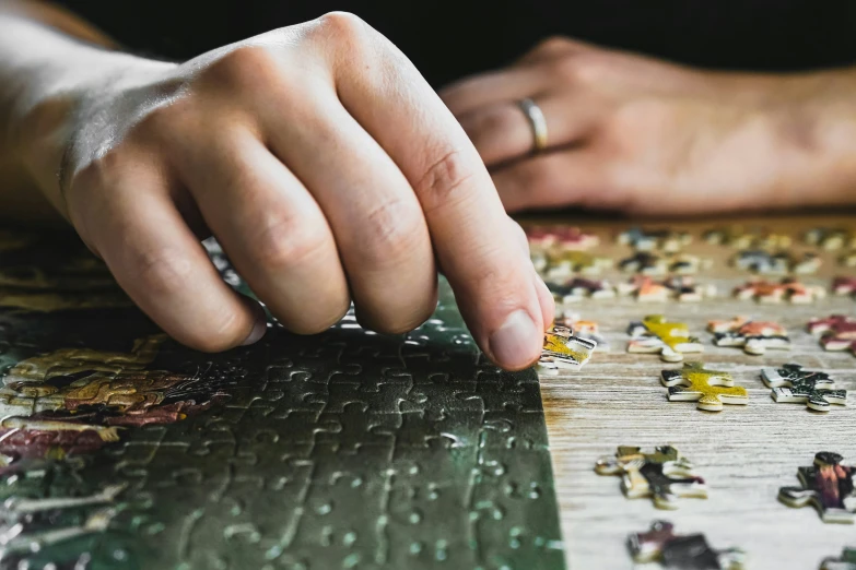 a man's hand putting ring on a puzzle piece