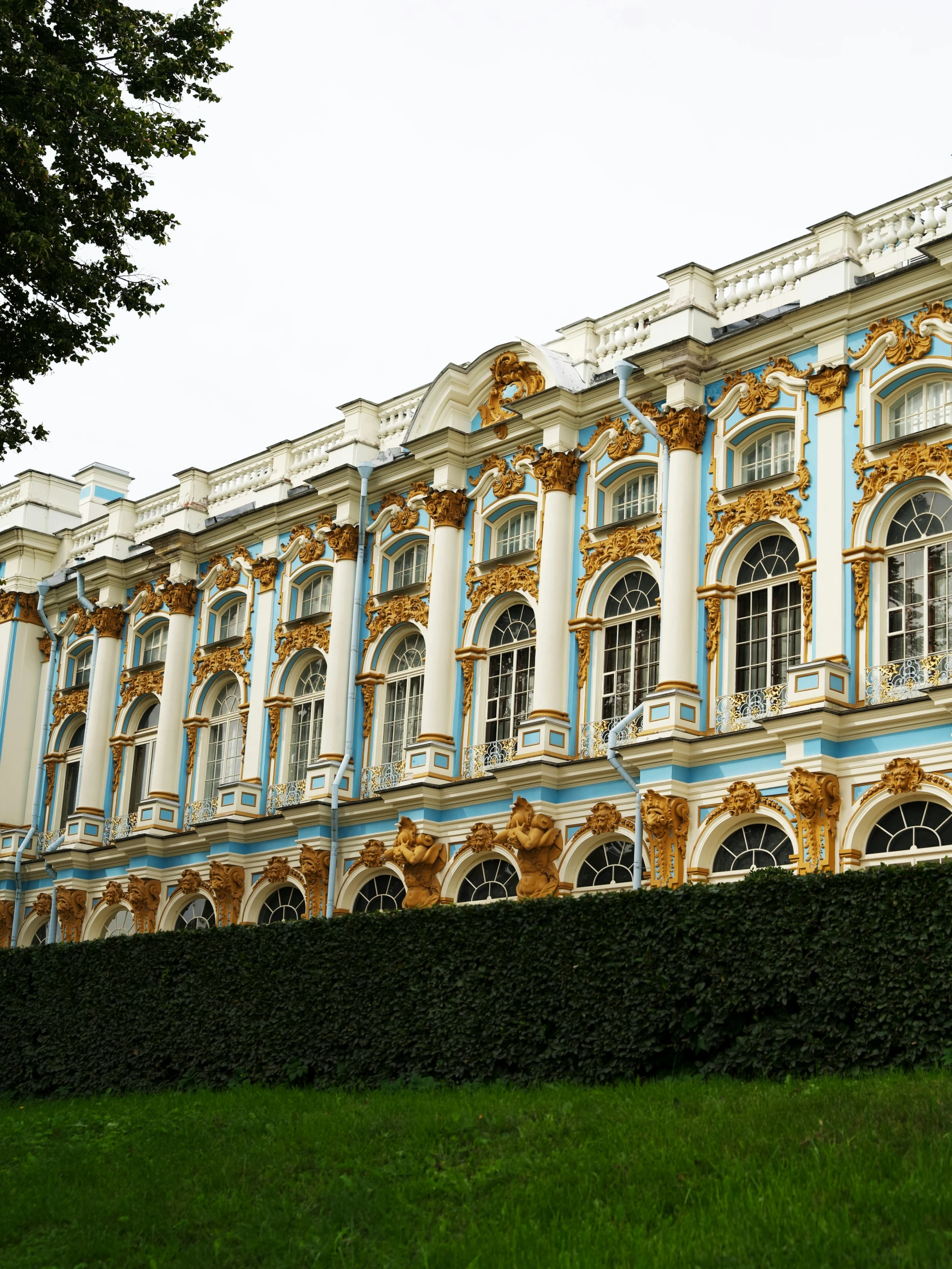 ornate building with golden accents and tall hedges